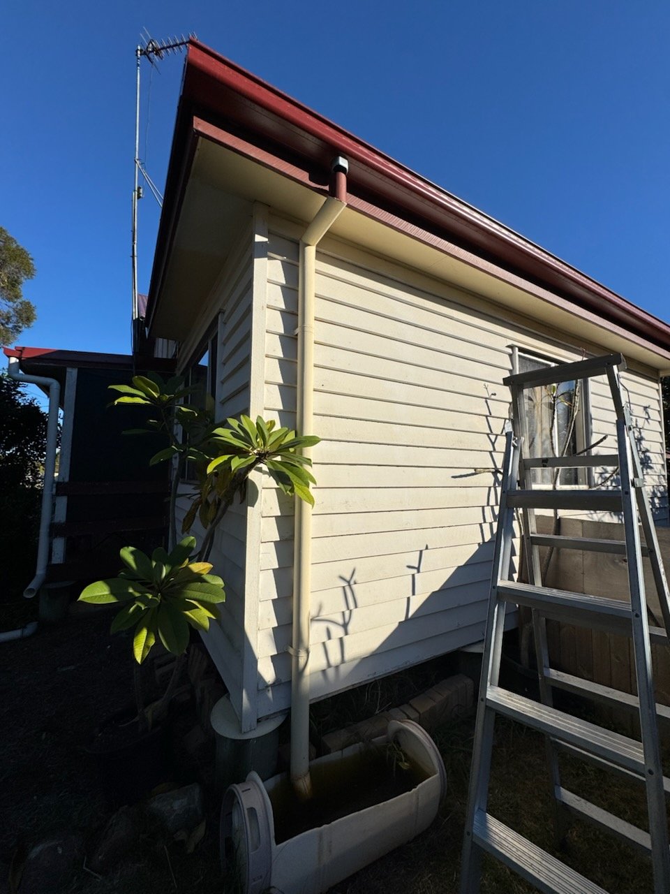 New red gutter and downpipe on a weatherboard cottage